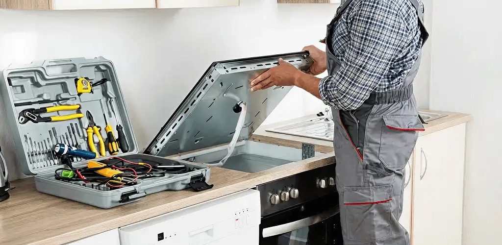 Handyman repairing a cooktop and checking wiring connections in Los Angeles, CA