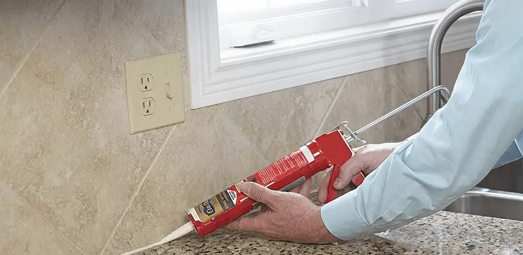 Handyman applying caulk along a kitchen backsplash and countertop seam in Los Angeles, CA