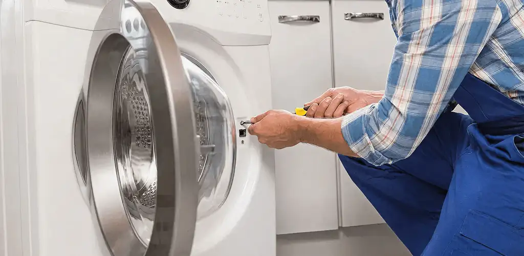 Handyman repairing a clothes dryer and checking electrical connections in Los Angeles, CA