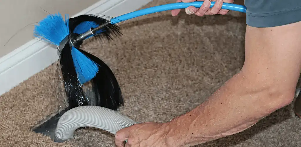 Dryer vent cleaning technician brushing lint from a vent line in Los Angeles, CA