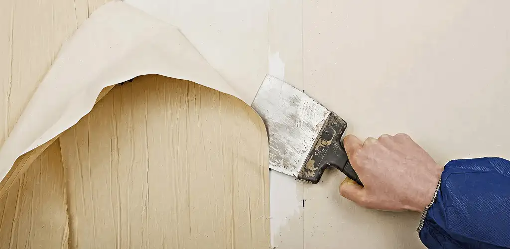 Handyman removing wallpaper with a scraper for wall preparation in Los Angeles, CA