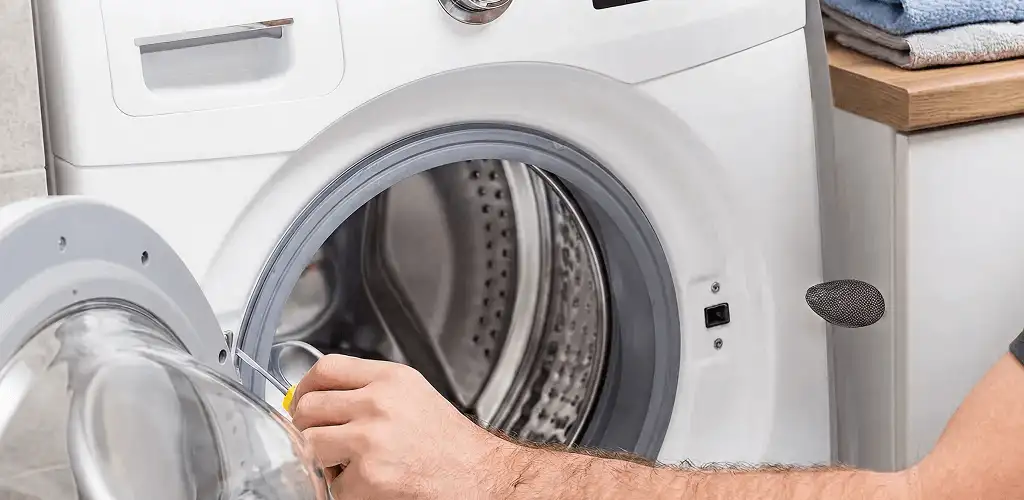 Handyman repairing a front-load washing machine and inspecting the drum in Los Angeles, CA