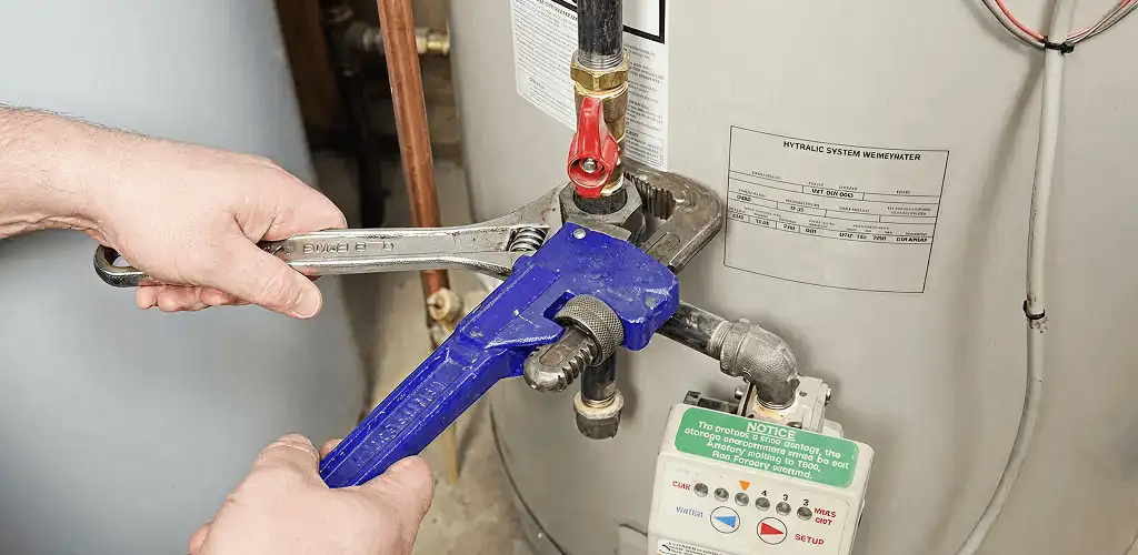 Water heater repair technician tightening the shutoff valve and supply line in Los Angeles, CA